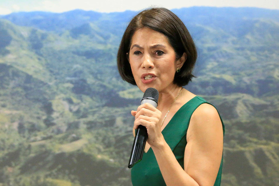 Ms Gina Lopez with the bacground of a mining site